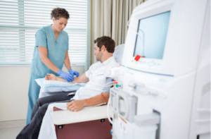 Mid adult female nurse injecting patient for renal dialysis treatment in hospital room