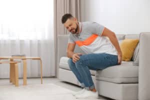 Man suffering from hemorrhoid on sofa at home