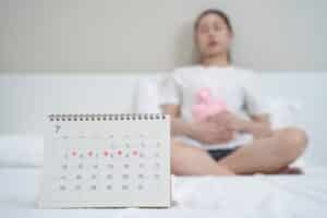 Close up calendar marking on menstruation period day and woman have stomach pain as background